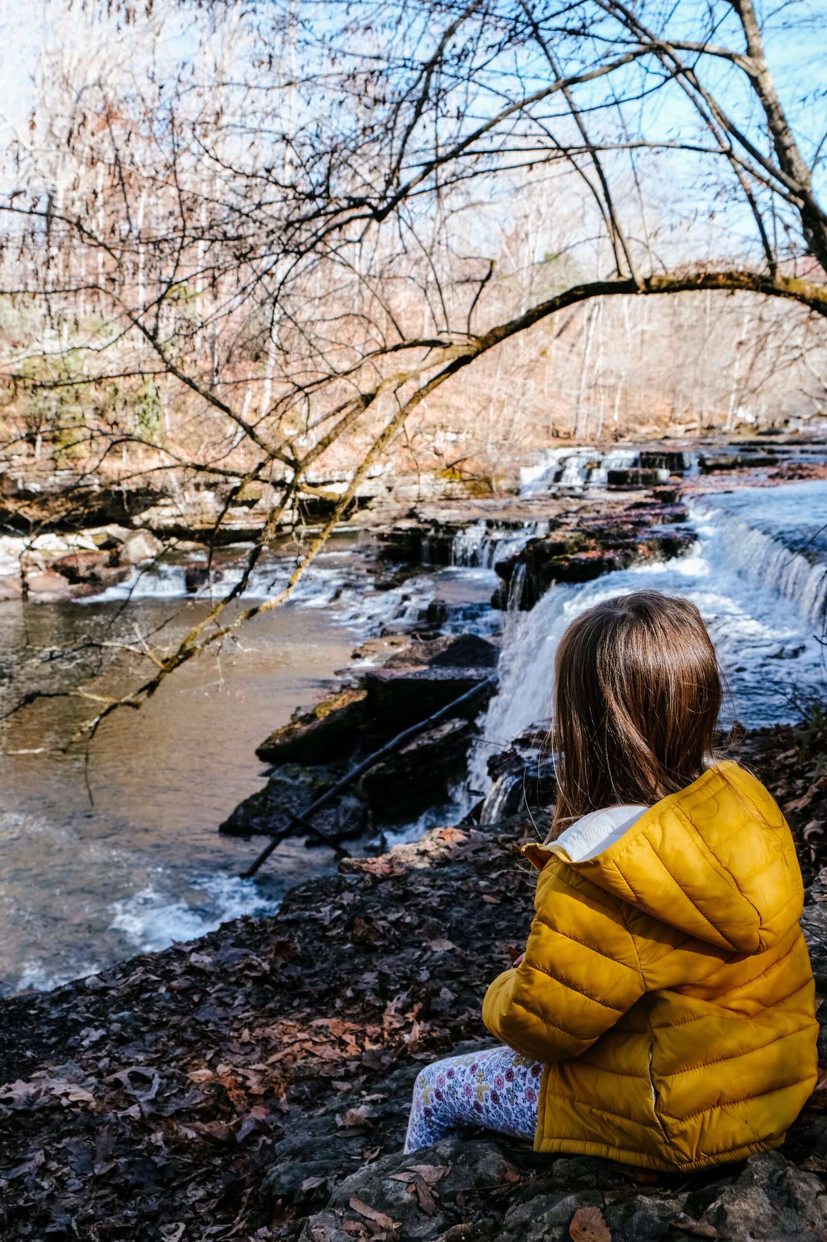 Young girl sitting on an overlook by a waterfall at Old Stone Fort State Park